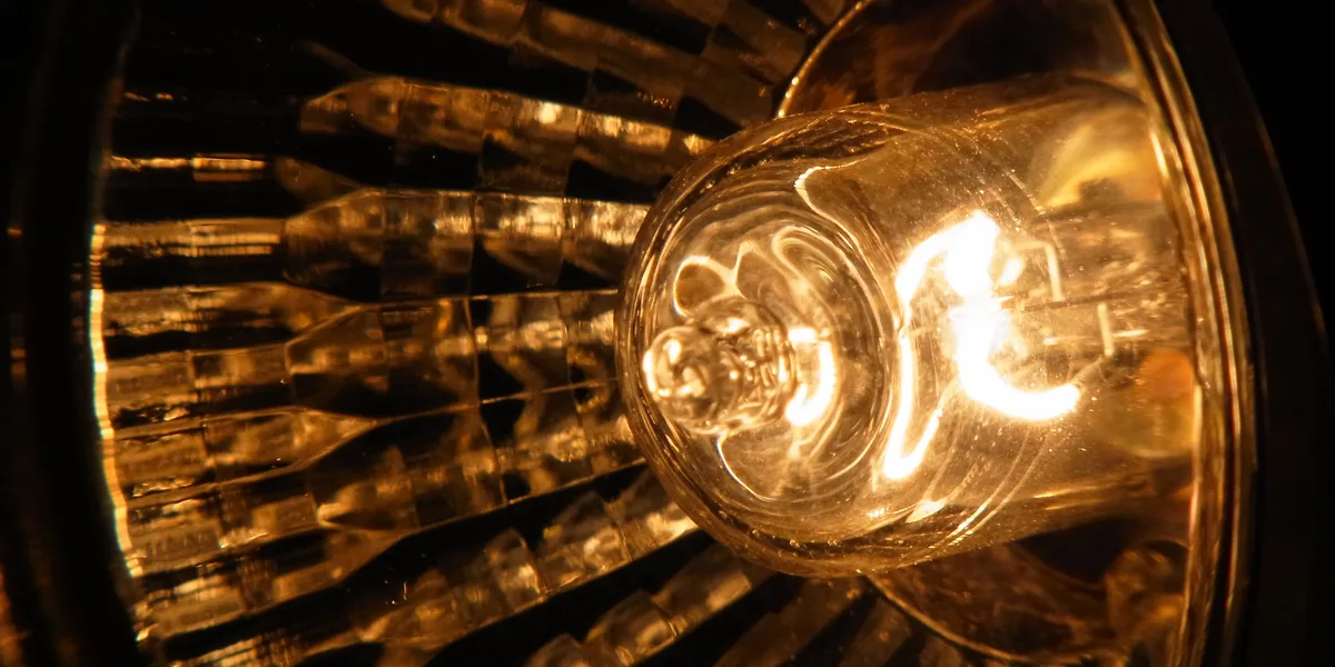 Halogenlampe in einem facettierten Glasreflektor, leuchtend vor dunklem Hintergrund