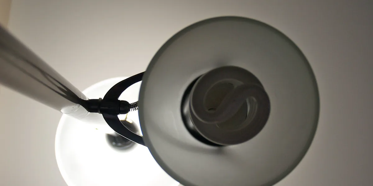 Zwei Lampenschirme von unten fotografiert, im vorderen eine gewendelte Kompaktleuchtstofflampe, dahinter ein hell leuchtender Schirm